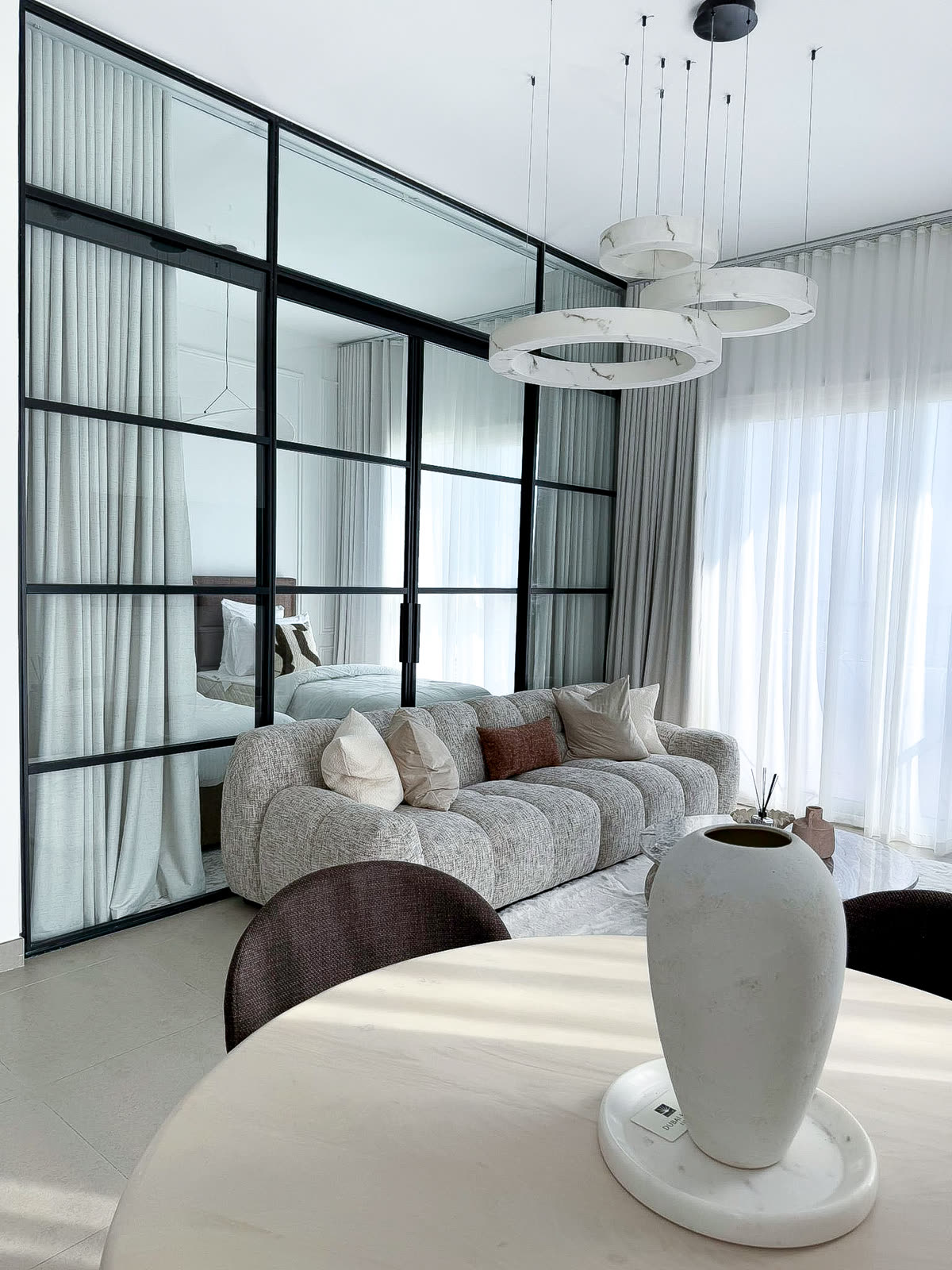 Salon contemporain réalisé par Proj&Co : verrière d'atelier noire, canapé modulaire et suspensions en marbre