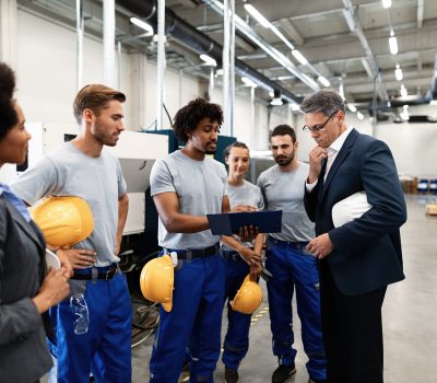 Company manager and African American worker cooperating while analzying production plans on a meeting in a factory.